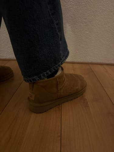 Close-up van een klant die de kastanjekleurige UGG Classic Ultra Mini laars draagt.