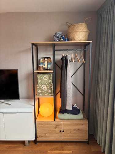 Recensent toont de gemonteerde Kledingkast LENNY in een kamer, gevuld met kleding en decoraties.