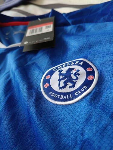 Primo piano della maglia del Chelsea di un cliente, che ne mostra lo stemma ricamato e il tessuto blu testurizzato.
