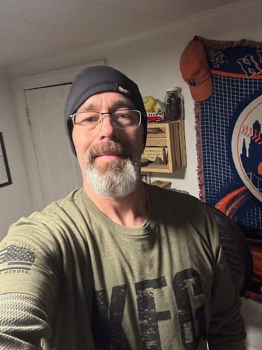 Reviewer in an olive green KFG long-sleeved shirt, showing the front graphic and sleeve detail.