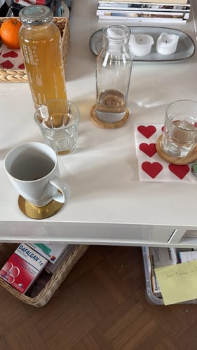 Kunde zeigt seinen fertigen, goldfarbenen Kombucha in einer Flasche auf einem Tisch.