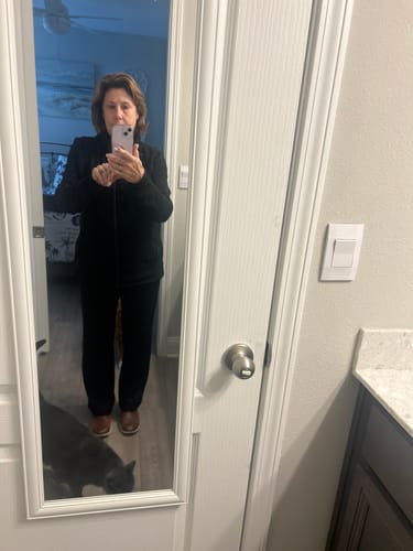 Reviewer in a full-length mirror selfie wearing the black Finley Zip Up Sweatshirt and black pants.