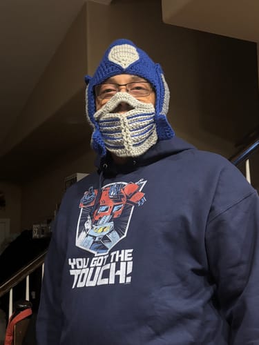 Customer wearing the navy Optimus Prime hoodie with a matching, blue and grey crocheted Optimus Prime mask.
