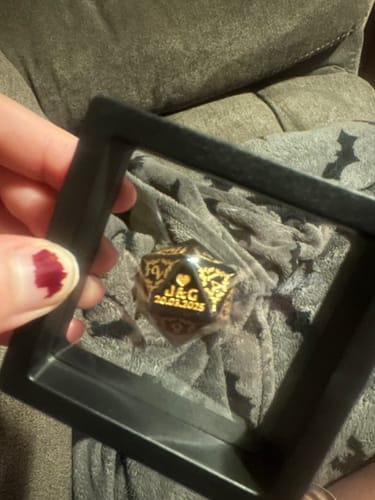Customer holding a display case with a personalized black and gold Custom Anniversary D20 Dice inside.