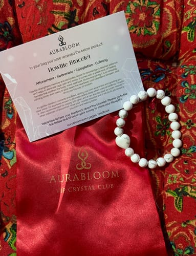 Reviewer's white Howlite bracelet from the VIP Crystal Club shown with its red satin pouch and info card.