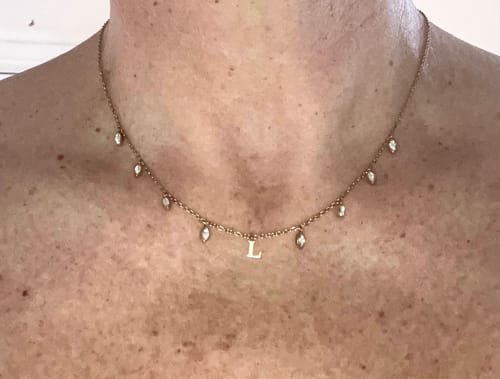 Reviewer wearing the delicate gold Initial Drop Necklace with an 'L' charm and cascading stones.