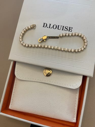Customer displays their shimmering Tennis Bracelet on its chic D.Louise packaging.