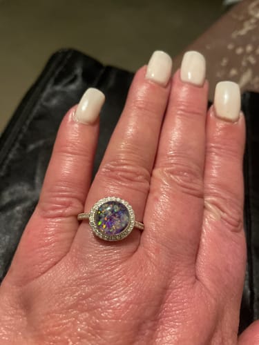 Customer wearing the Bedazzled Circle Opal Cremation Ring, showing its purple and silver colors.
