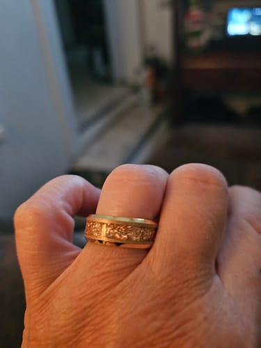 Close-up of a customer's hand wearing the gold Aureum ring, highlighting the textured foil inlay.