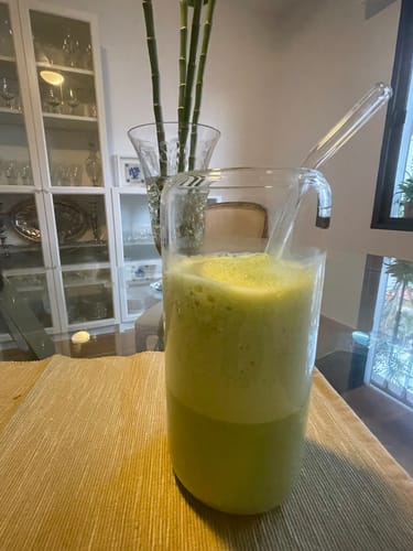 Reseñador mostrando el Té matcha del mes preparado, espumoso y servido en un vaso alto de cristal.