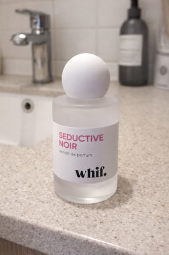 Customer's Seductive Noir perfume in a frosted bottle with a round cap, on a bathroom counter.