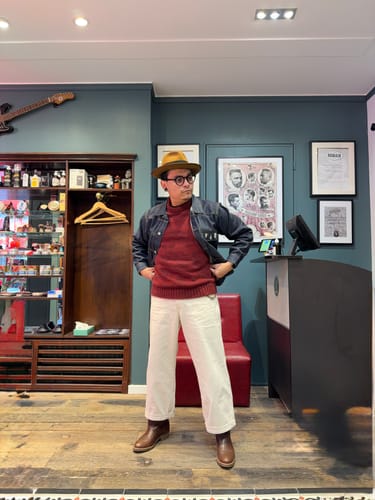 Reviewer standing indoors, wearing the off-white USN Herringbone Deck Pants with a red sweater and brown boots.