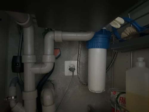 Rezensent zeigt den installierten MAUNAWAI® PITEC Küchenfilter unter der Spüle.