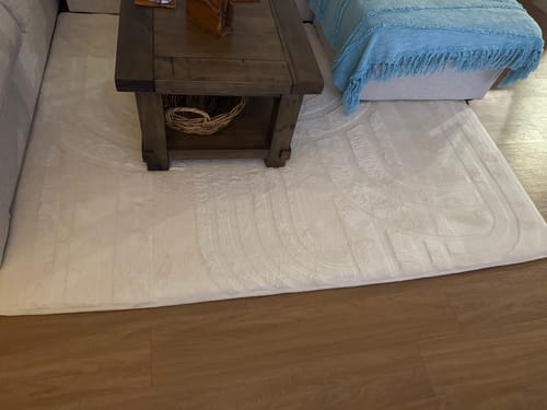A reviewer's soft, vanilla cream Mellow Mat looking great in their family room under a coffee table.