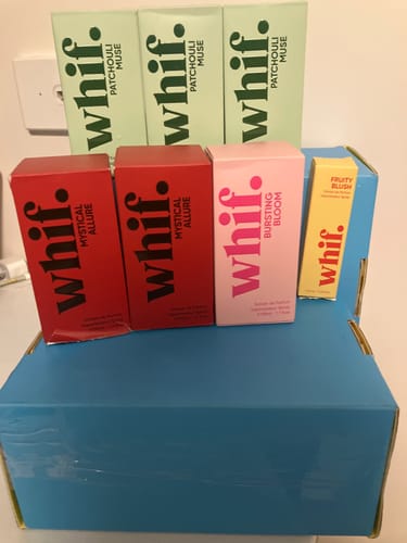 Customer displays their collection of colorful Whif perfume boxes, including Patchouli Muse and Mystical Allure.