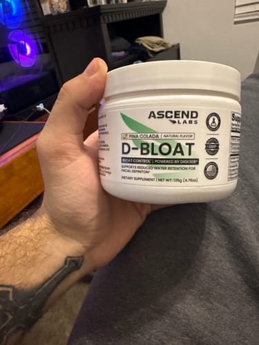 Reviewer holding a white tub of Ascend Labs D-BLOAT powder in Pina Colada flavor.
