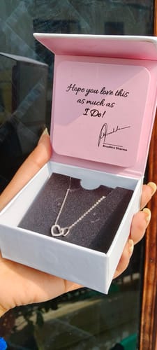 Customer's hand holding the open white and pink box, displaying the Silver Pretty Love Necklace.