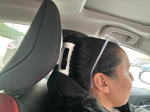 Reviewer wearing a white cloud clip in their hair, resting their head comfortably against a car headrest.