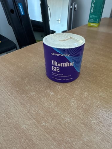 Avis d'un client : le flacon violet de Vitamine B12 posé sur une table en bois.