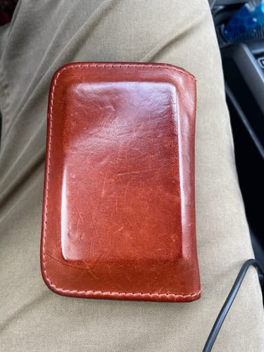 Customer's 'Buck Brown' Vertical Leather Wallet, showing a well-worn patina while resting on their lap.