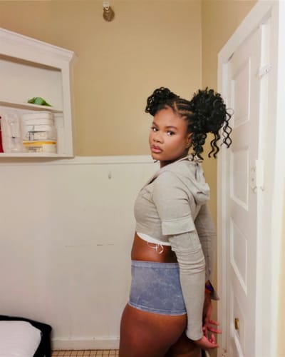 Reviewer showing the fit of the grey Seamless Micro Mini Shorts from the side while posing indoors.