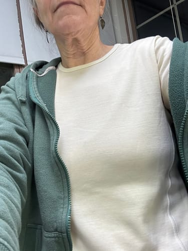 Reviewer wearing the Hannah Long Sleeve Top in Buttercream as a base layer under a partially unzipped hoodie.