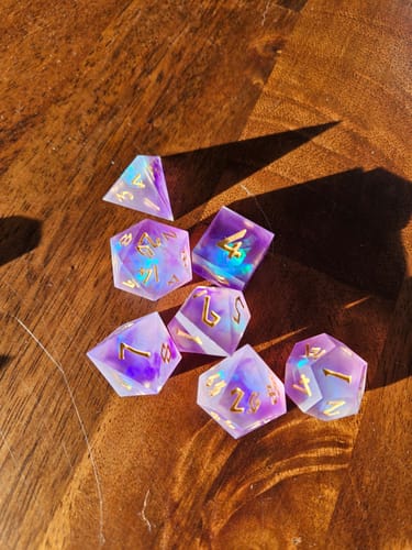 Reviewer's Mystic Divination dice set in gorgeous lilac resin with blue foil, displayed on a wooden table.
