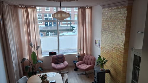 Recensent toont de beige Plu hanglamp in een stijlvol retro interieur.