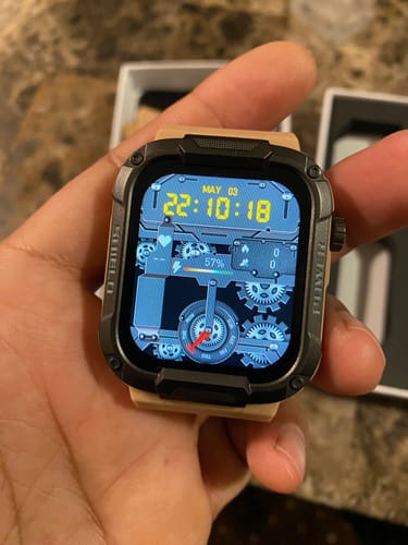 Customer holding the Gard Pro Ultra smartwatch with a rugged case, tan band, and an active, detailed digital display.