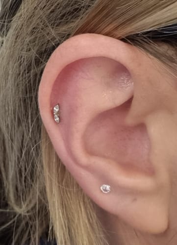 Reviewer's ear showing the Gilded leaf flatback Silver earring with its two stacked crystals in a helix piercing.