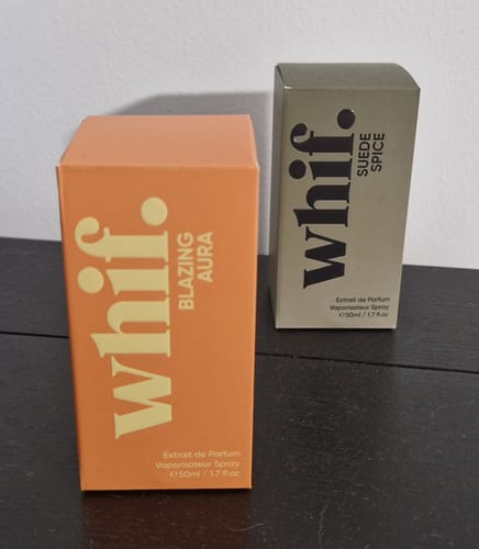 Customer's new Blazing Aura fragrance in its orange box, shown next to another fragrance on a dark table.