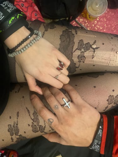 Customer showing their red coffin-shaped Promise Ring while holding hands with their partner.