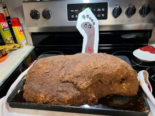 Customer's USDA Prime Brisket covered in seasoning on a baking sheet before cooking in a kitchen.