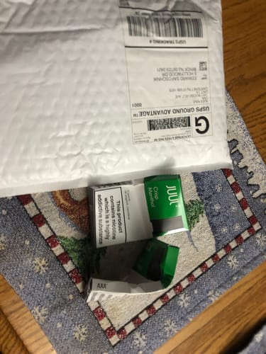 Customer's photo of crushed and bent boxes of Crisp Menthol JUUL2 Pods next to the shipping mailer.