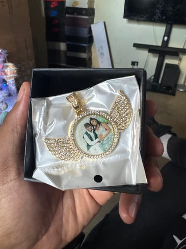 Customer holding the Diamond Studded Angel Wing Photo Necklace with a personal photo inside its black gift box.