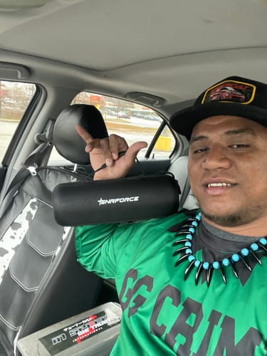 Reviewer holding the black Enrforce Bluetooth Speaker in its carrying case inside a car.