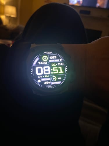 Close-up of a customer's Gard Pro Ultra 3 watch on their wrist, with the bright digital display lit up in a dark room.