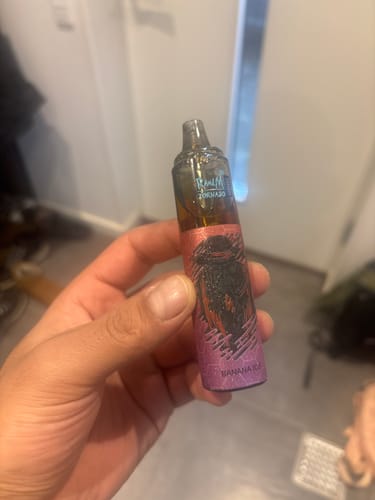 Customer holding a RandM Tornado 7000 disposable vape with purple and pink 'Banana Ice' branding.