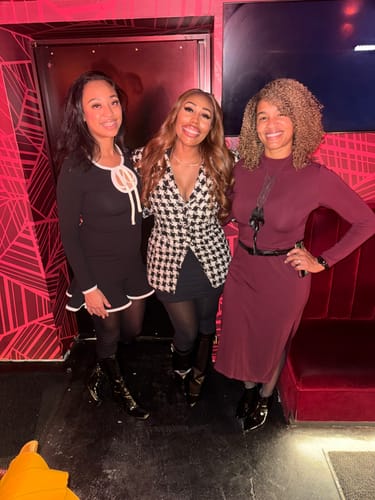 Customer wearing the Tweed Houndstooth Suited Blazer with a black mini skirt and boots, posing between two other people.