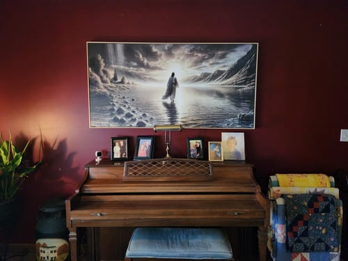 Customer's framed 'Walking on Water' wall art hanging on a dark red wall above a piano.