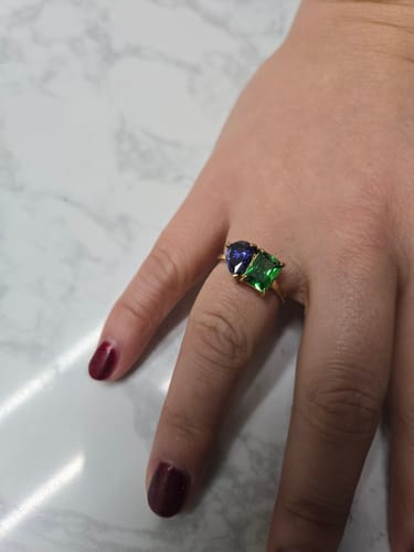 Customer wearing the gold Toi Et Moi Birthstone Ring with a green emerald-cut and a deep blue pear-cut stone.
