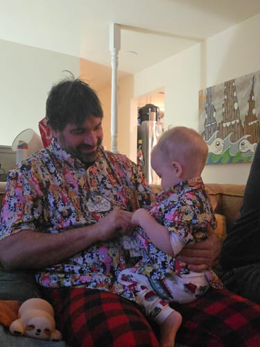 Customer and a small child wearing matching Bluey "Primary Pals" shirts while sitting on a couch.