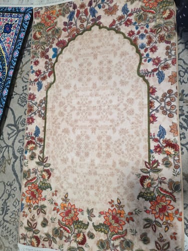 Customer's Barakah Padded Prayer Mat laid flat, showing its intricate floral border and beige arched center.