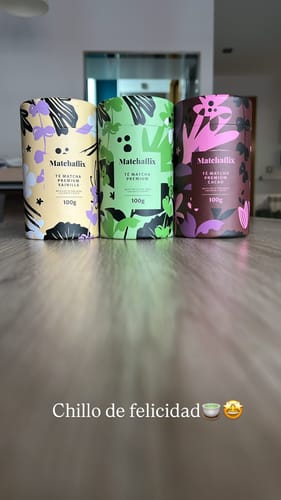 Cliente muestra tres botes de té Matchaflix sobre una mesa: premium, vainilla y cacao.