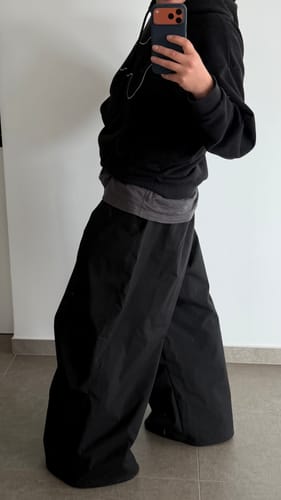 Reviewer in a mirror selfie showing the side view of their oversized black snow anorak.