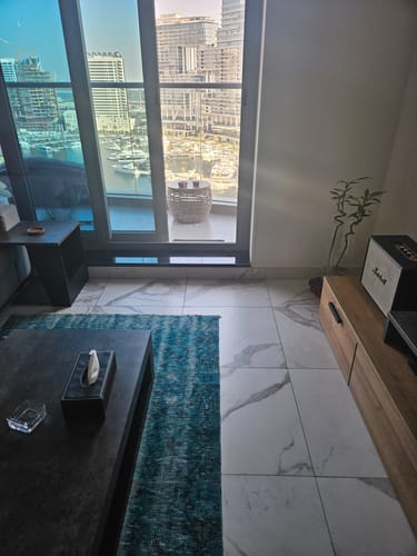 A customer's teal Anatolian hand-knotted carpet in a modern living room with a large window view.