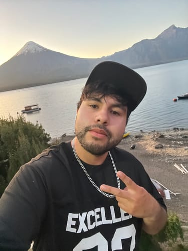 Cliente usando la Cadena Cuban Link 8mm en una selfi al aire libre, con un lago y una montaña de fondo.