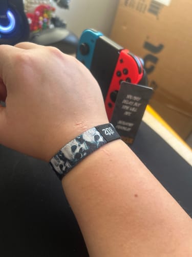 Customer wearing the Carpe Diem Bracelet with a skull pattern on their wrist, with the collector card visible in the background.