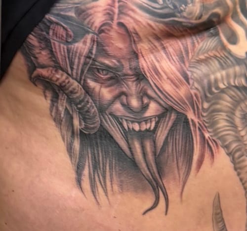 Close-up of a customer's detailed black and grey tattoo of a horned demon, completed during a session using Painless Tattoo cream.