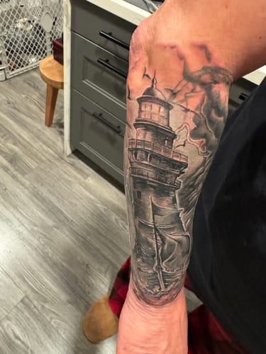 Reviewer's arm showing a large lighthouse tattoo, completed using the Painless Tattoo Spray.